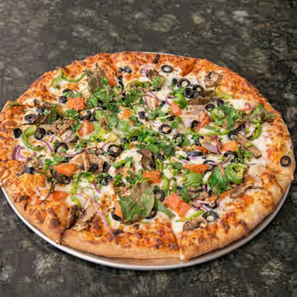 A whole pizza with green peppers, red onions, black olives, mushrooms, and cilantro on a dark countertop.